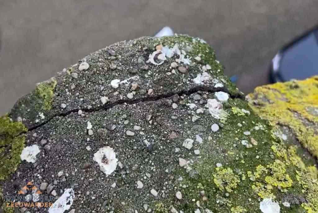 Beschadigde en verweerde nokvorst met scheuren en mos in Leeuwarden